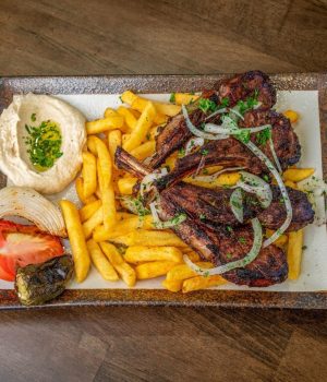 Flame-grilled lamb chops platter served with crispy French fries, hummus, and salad in Temple Terrace